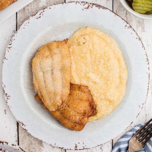 Fried catfish and cheese grits on a serving plate.