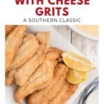 Plate of fried catfish fillets with lemon wedges next to a bowl of cheese grits on a white table.