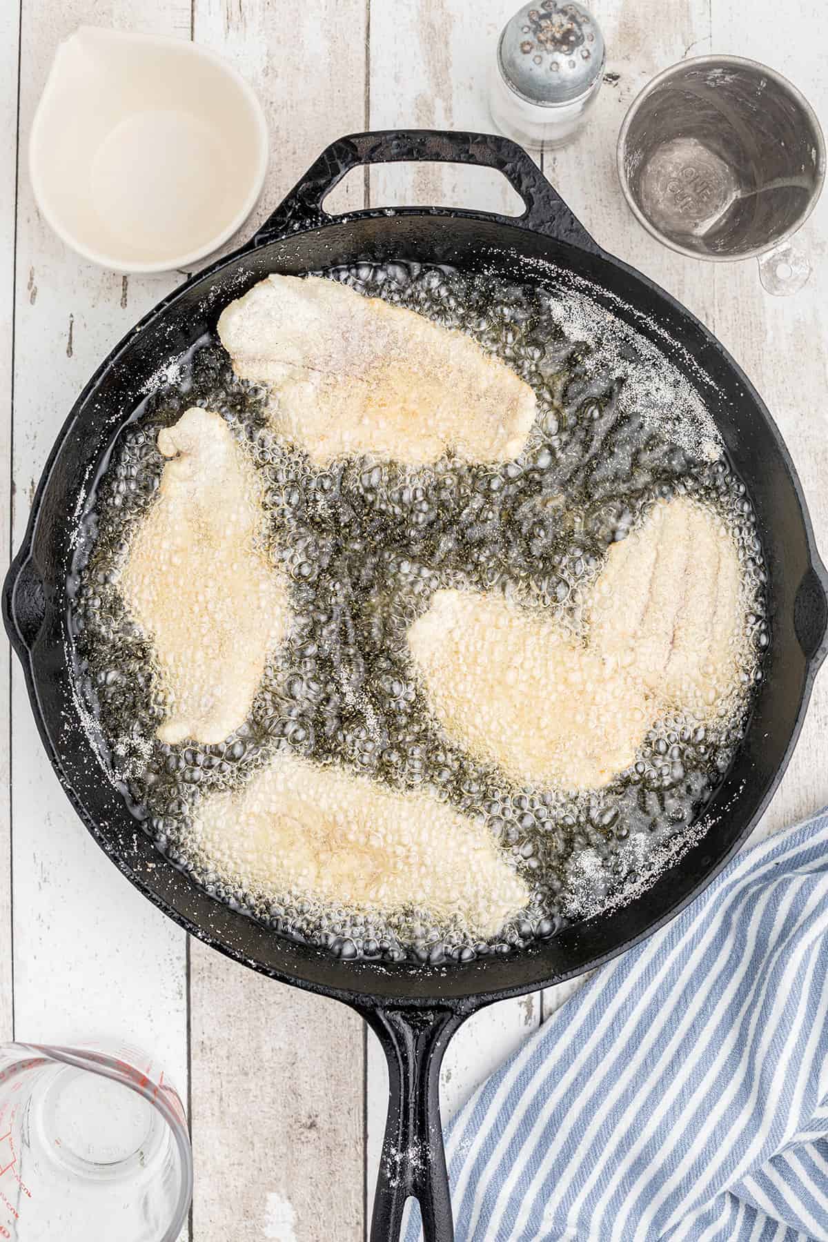 Catfish frying in a skillet.