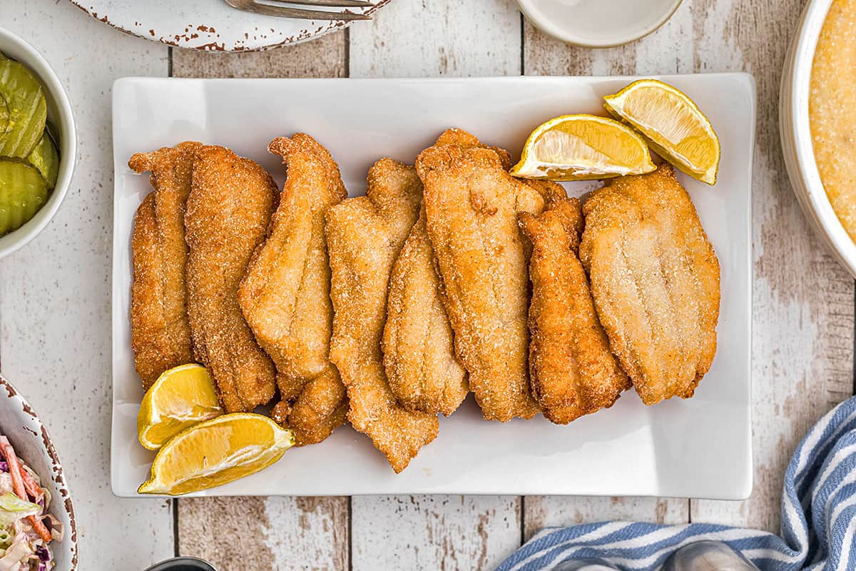 Finished fried catfish fillets on a white tray.