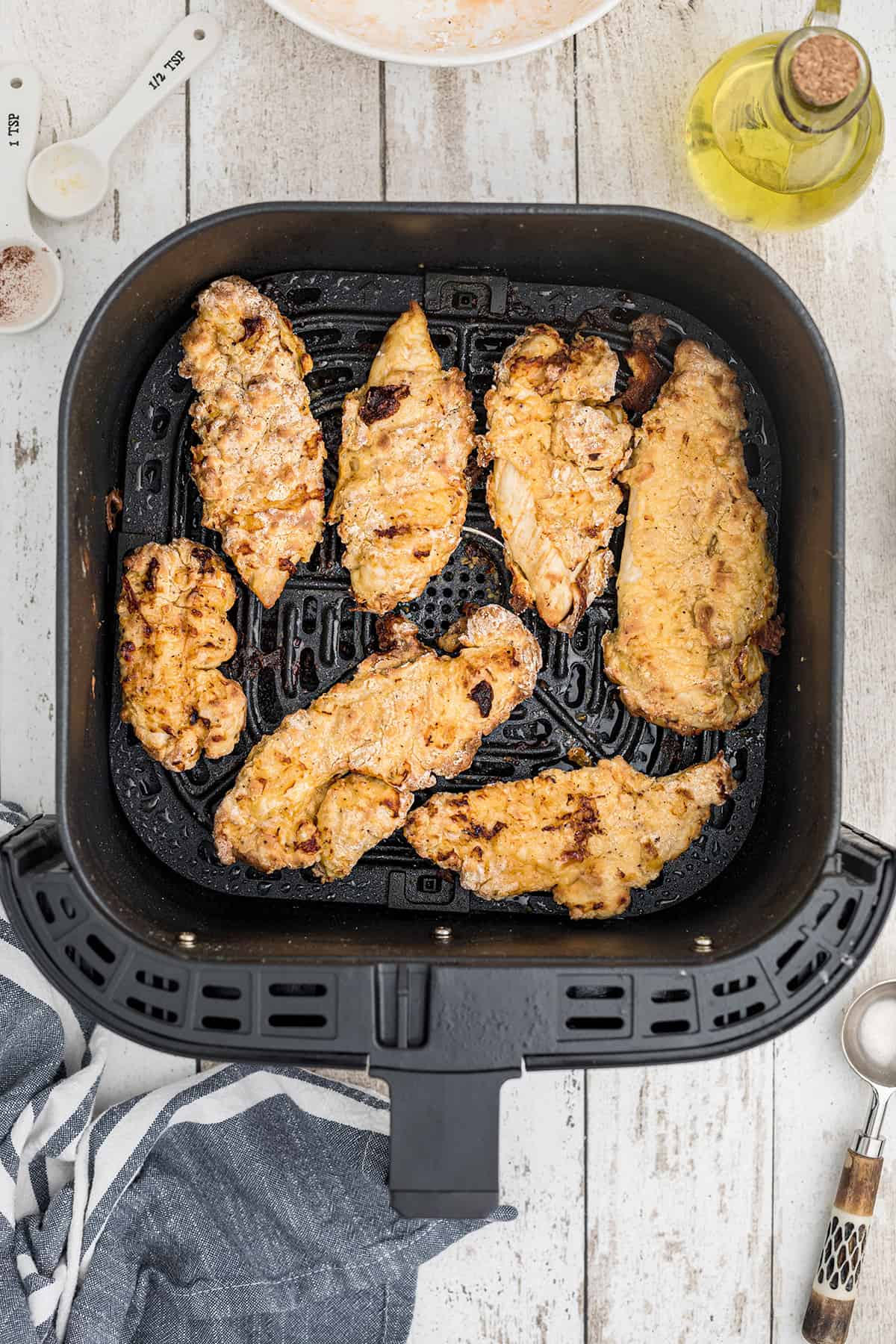 Chicken turned to cook on second side in air fryer basket.