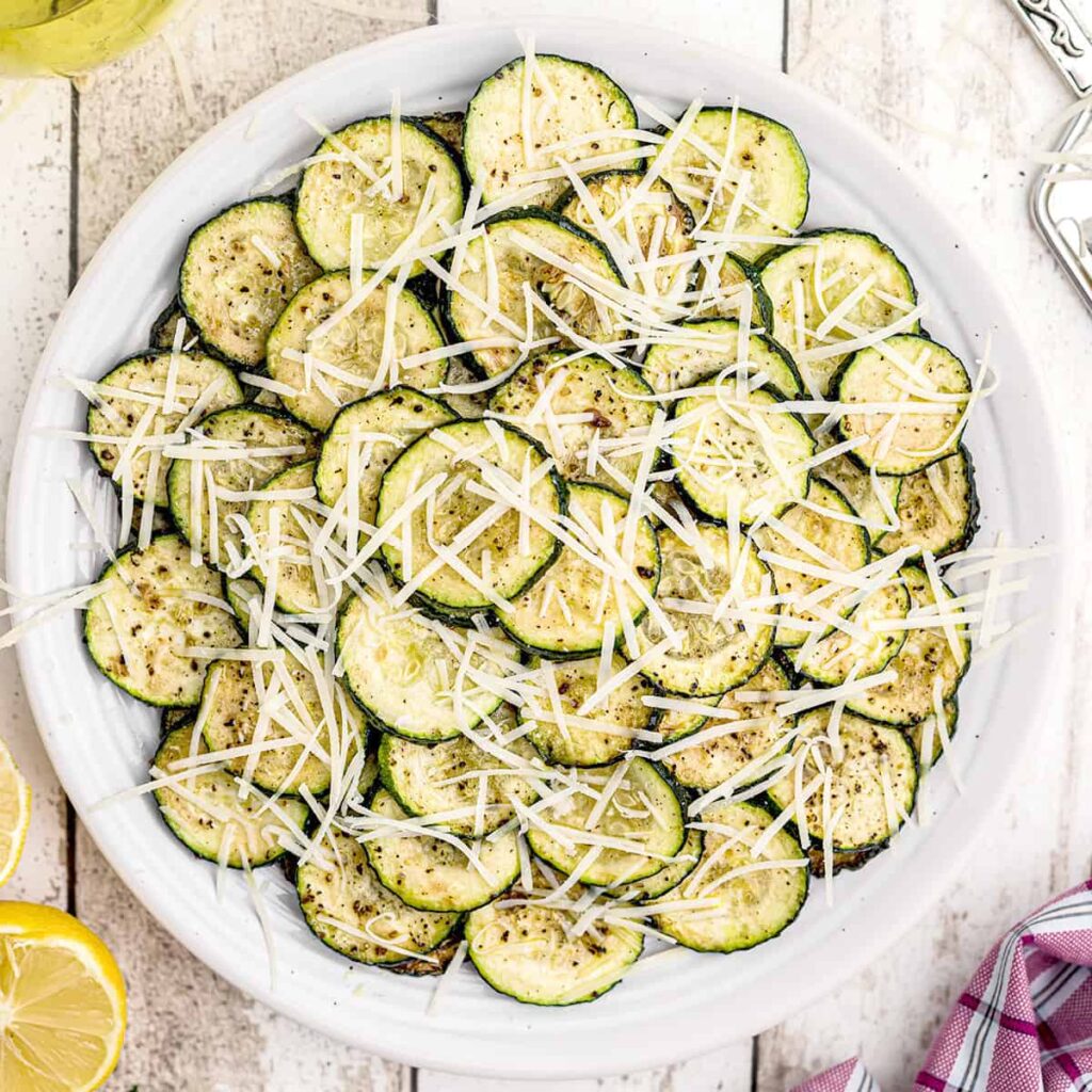 Finished pan fried zucchini on a white serving plate.