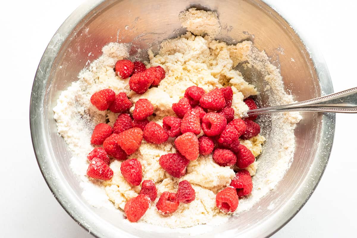 Fresh raspberries added to dough in mixing bowl.