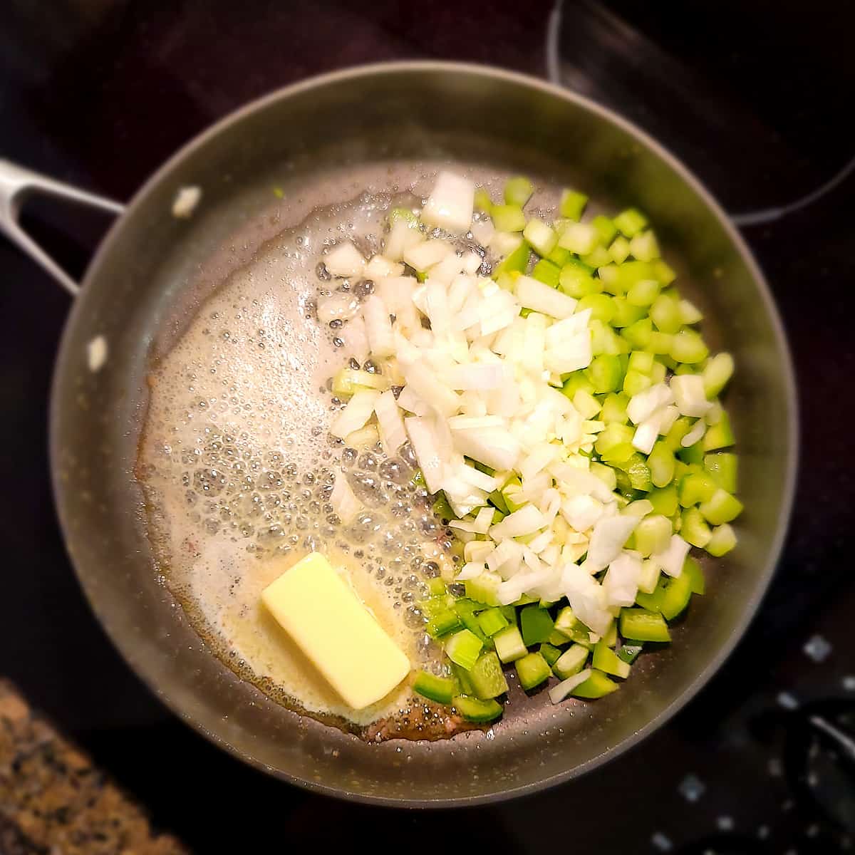 Butter and vegetables in a skillet.