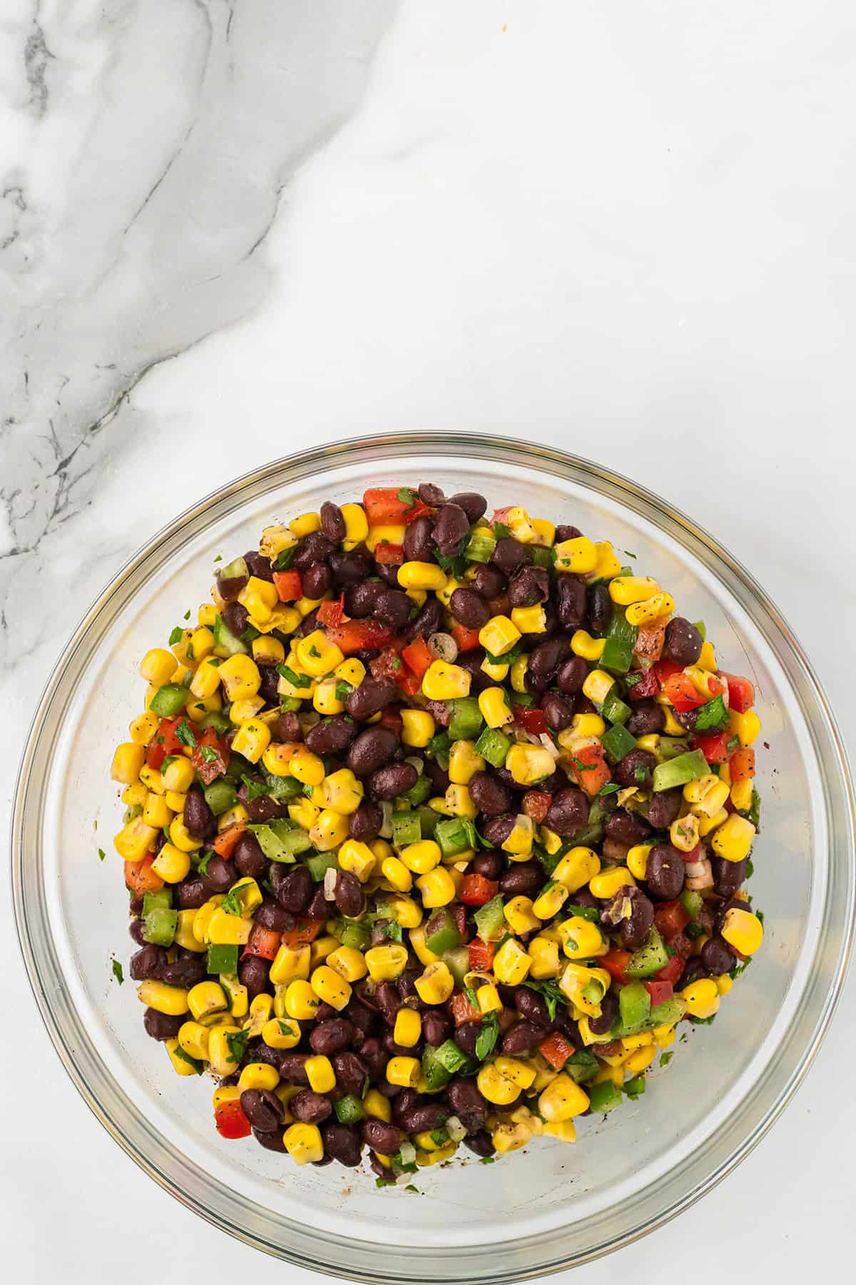 Salad ingredients mixed together in a mixing bowl.