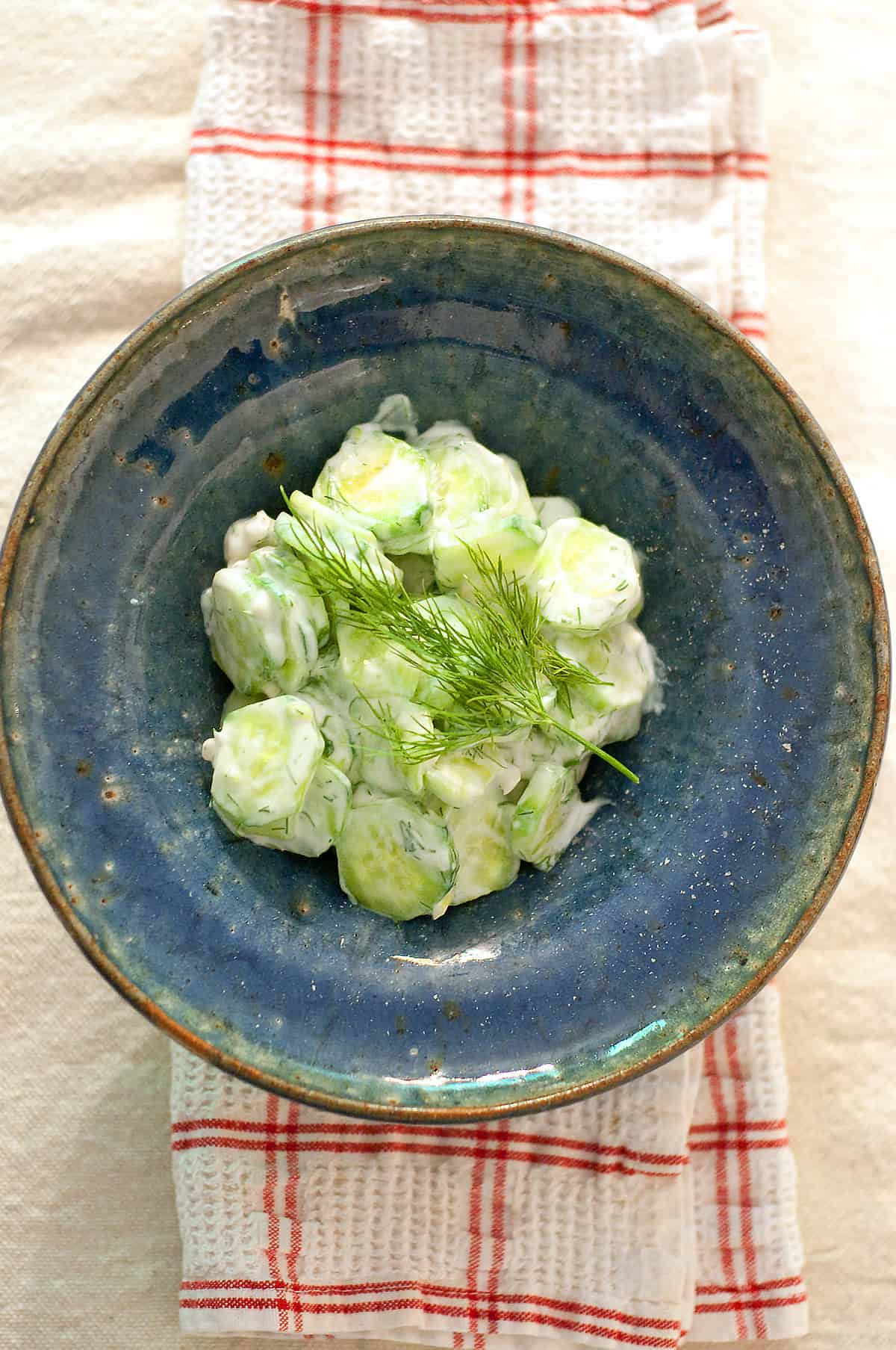 Creamy cucumber salad in a blue bowl.