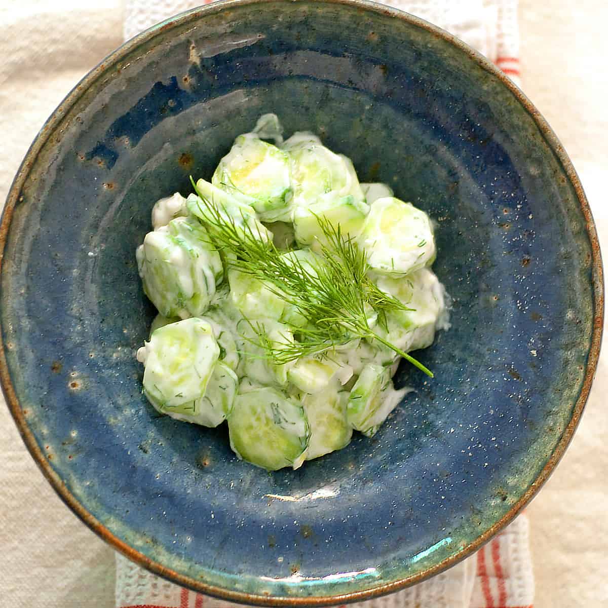 Creamy cucumber salad in a blue bowl.