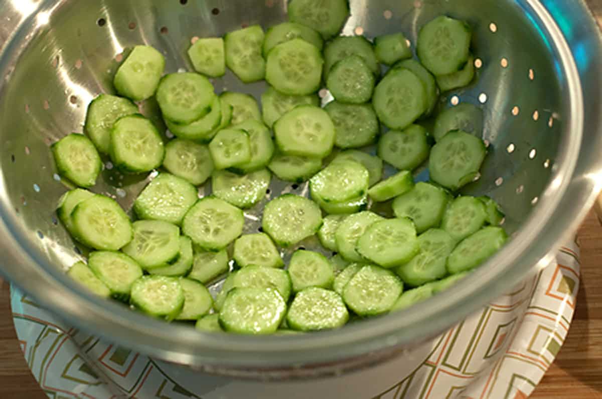 Cucumber slices draining in a colander.