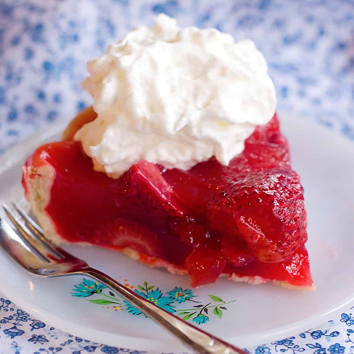 A serving of fresh strawberry pie on a saucer.