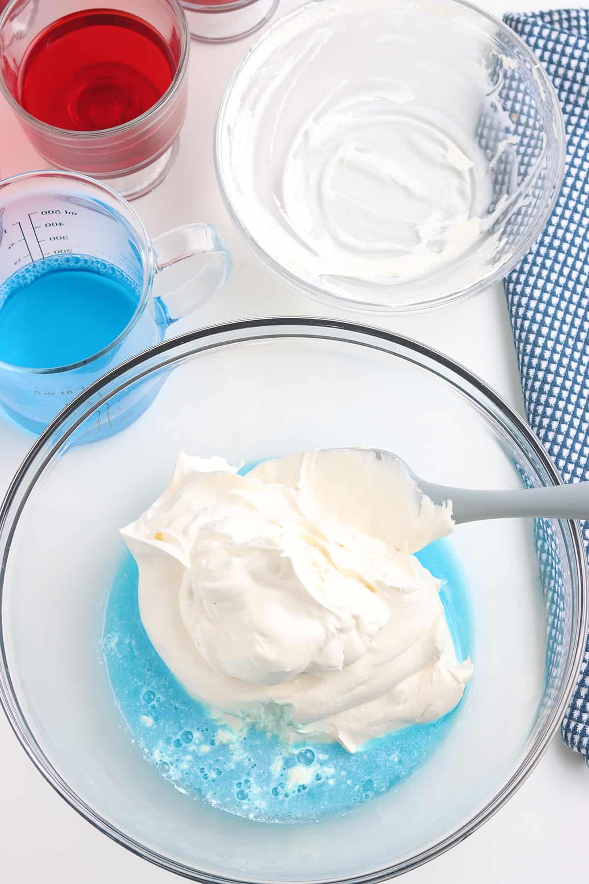 Folding whipped topping into blue gelatin.