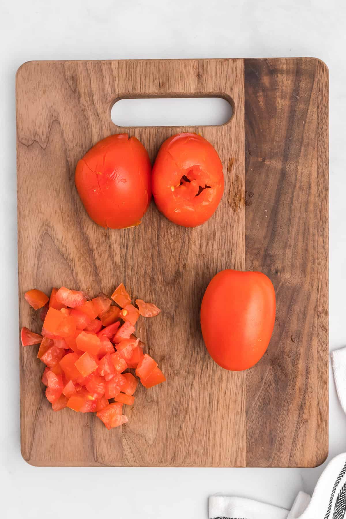 Tomatoes being prepared for the salad on a wooden board.