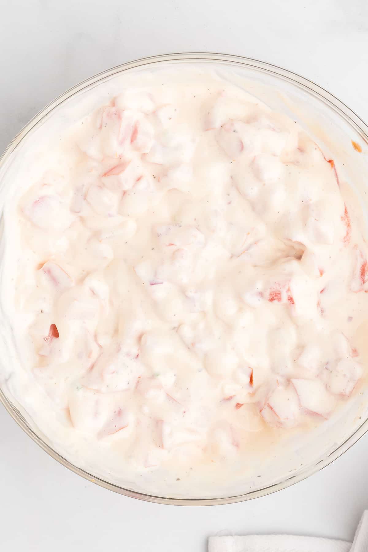 Diced tomatoes and mayonnaise mixed in a bowl.