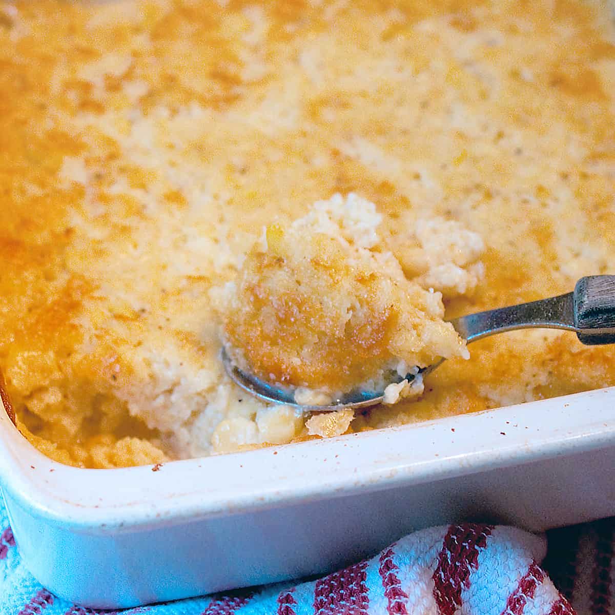 Finished baked corn casserole in a white baking dish.