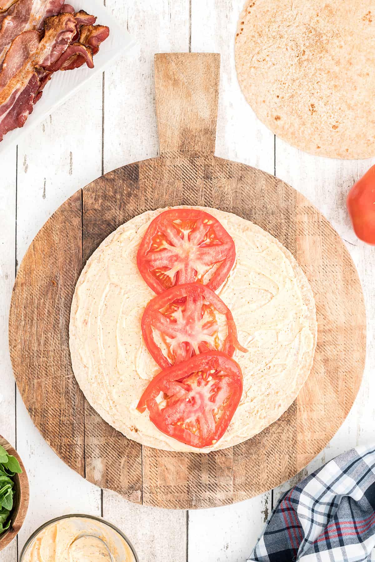 Tomato slices on to of mayonnaise in a wrap.