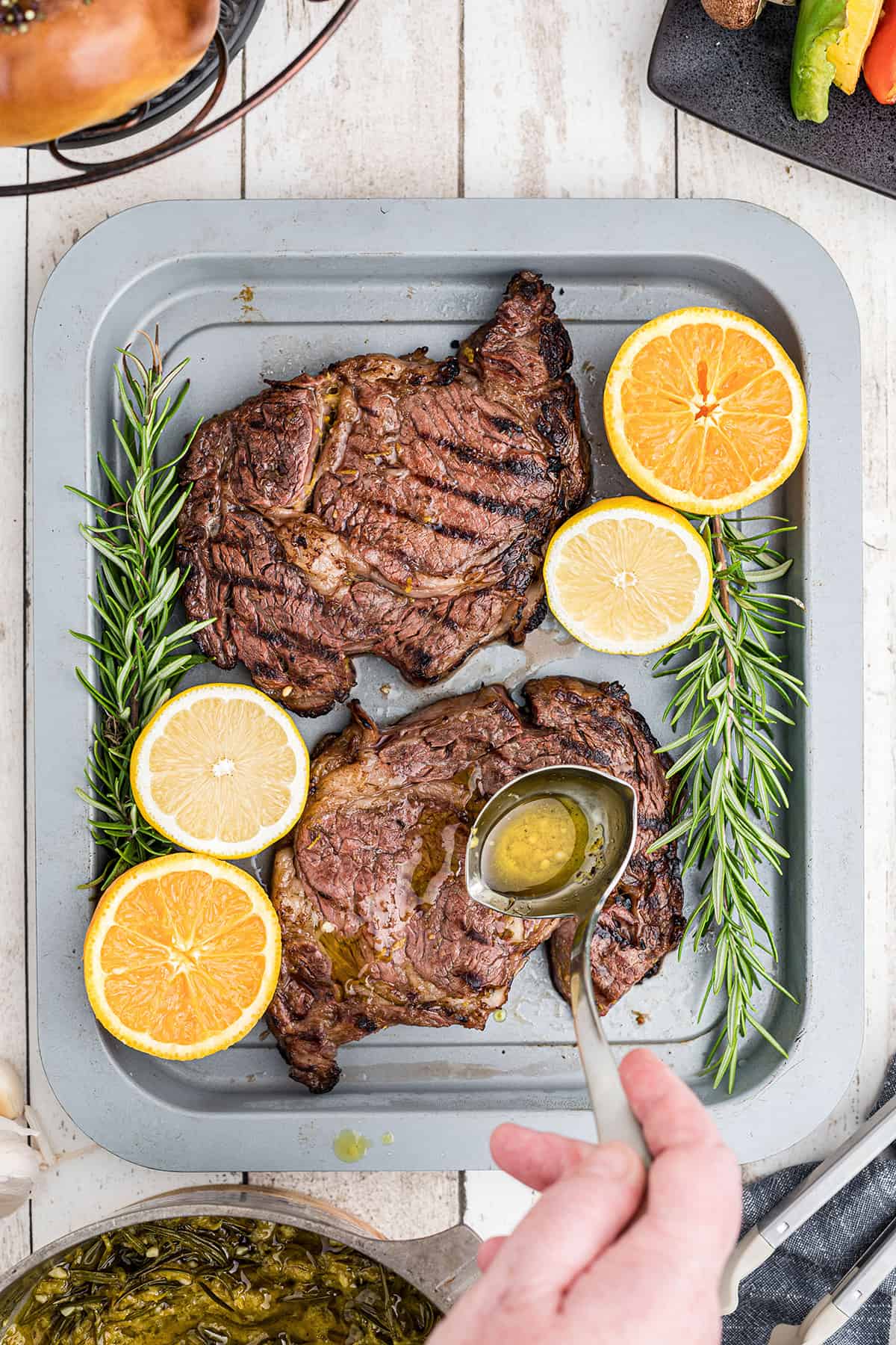 Drizzling marinade over steaks.