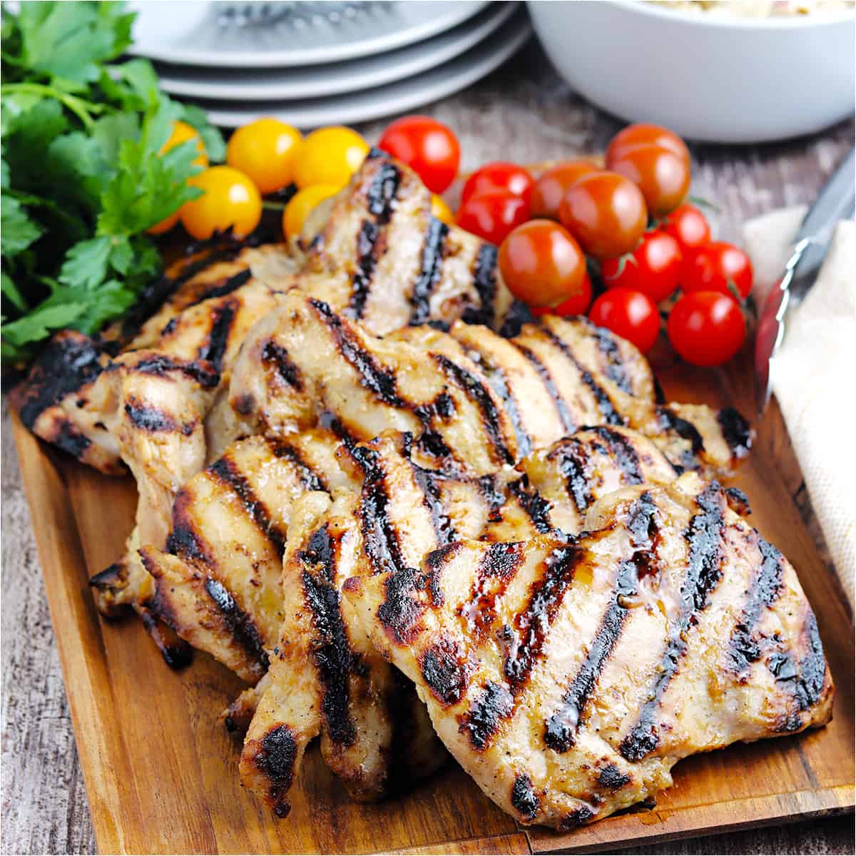 Finished grilled chicken thighs on a wooden board.