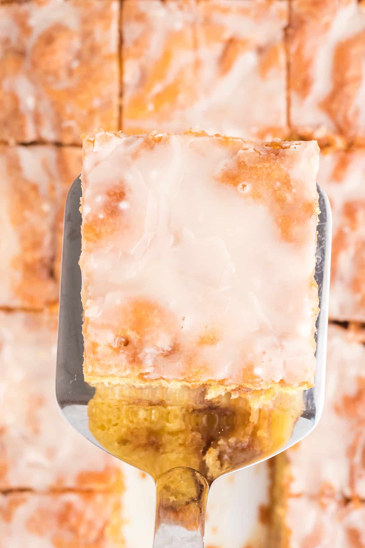 A spatula holding a serving of homemade honey bun cake.