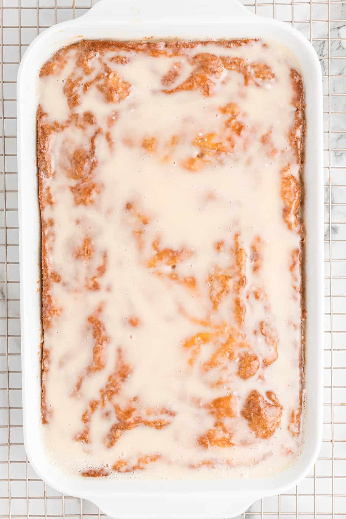 Cooled cake topped with vanilla glaze.