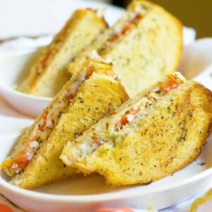 A caprese grilled cheese sandwich halved and plated.