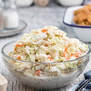 A glass serving bowl filled with coleslaw.