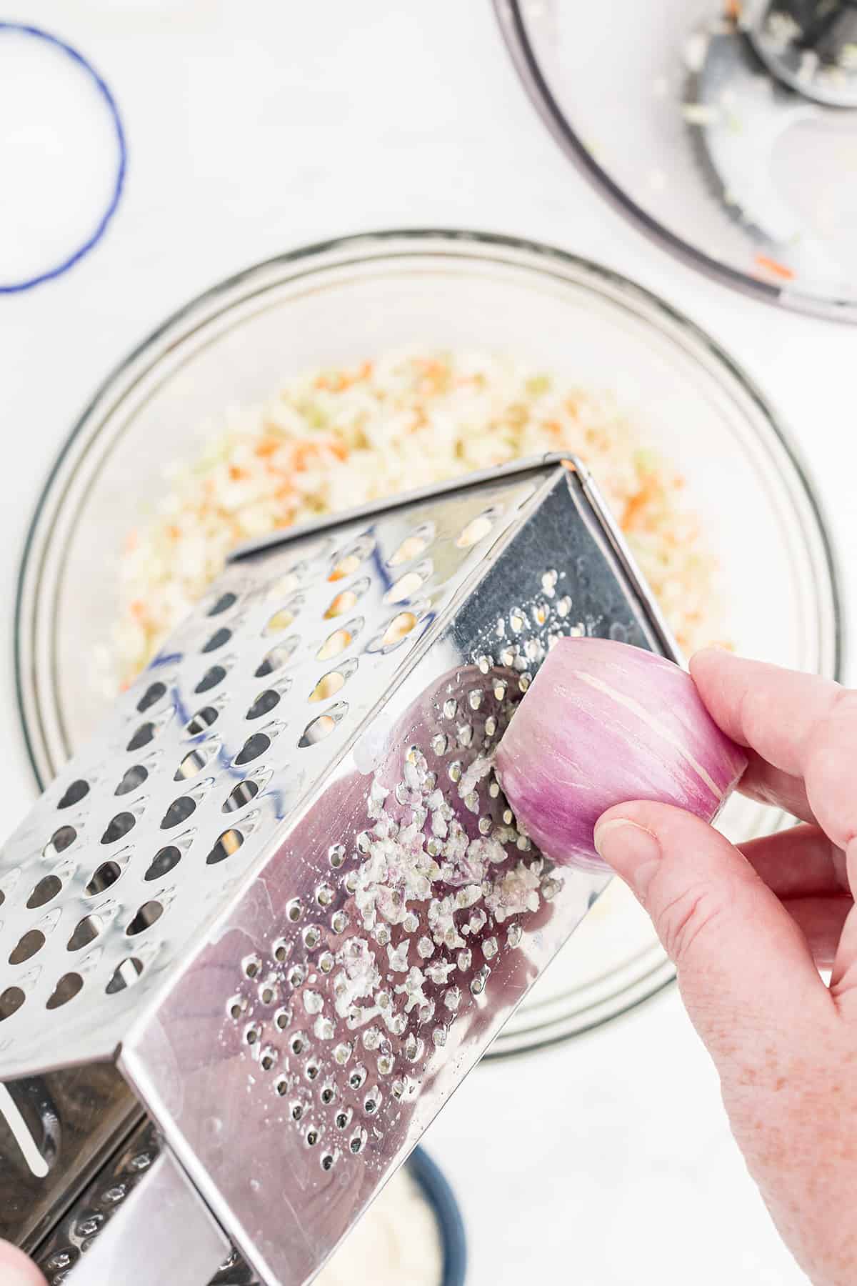 Grating a shallot into the bowl.