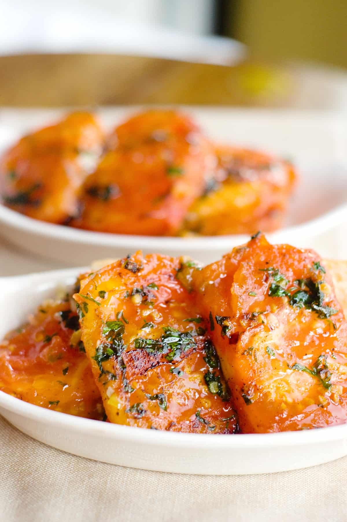 Garlic fried tomatoes in a small white serving bowl.