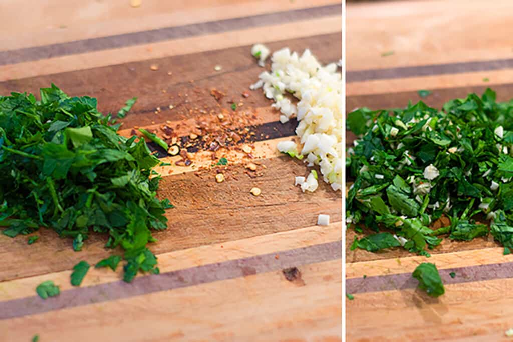 Chopped fresh herbs, minced garlic, and red pepper flakes on a wooden cutting board.