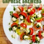 A white plate of caprese skewers with cherry tomatoes, mozzarella balls, basil, and chopped herbs, drizzled with olive oil, on a wooden surface. Text overlay reads Light & Fresh Caprese Skewers.