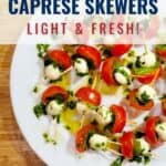 White plate with caprese skewers made of cherry tomatoes, mozzarella balls, and basil, drizzled with olive oil and herbs, placed on a wooden surface. Text overlay promotes the dish.