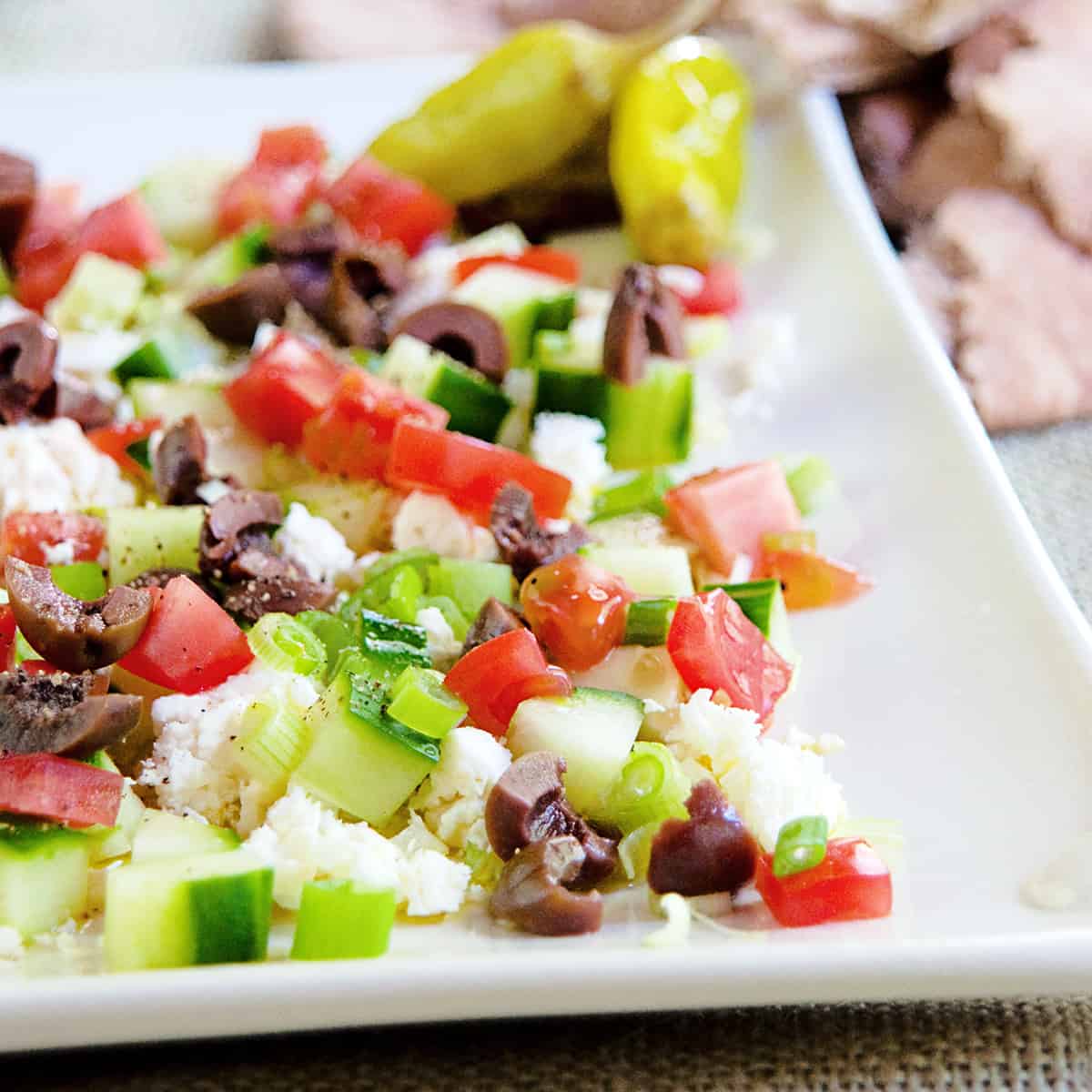 Finished layered feta dip on a white platter.