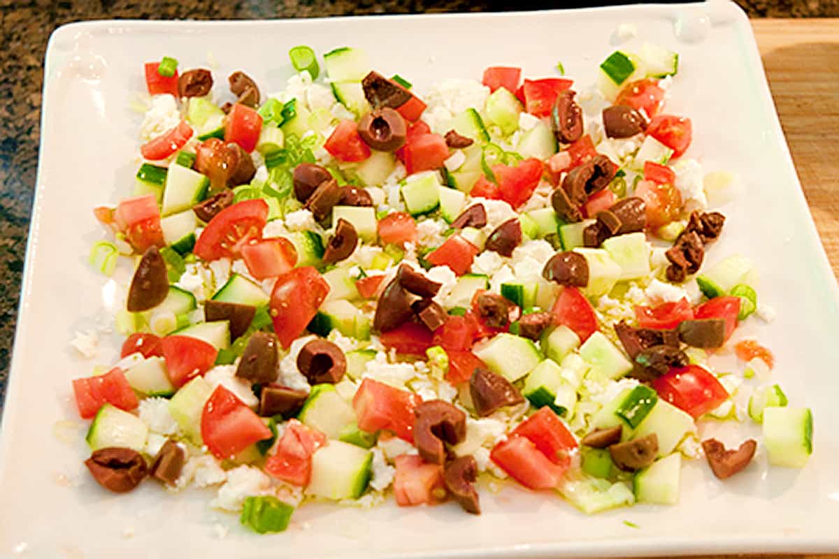 Olives and tomatoes added to layered dip.