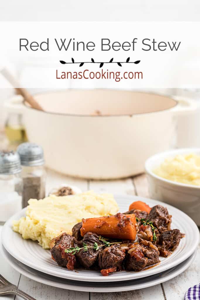 Beef stew on a plate alongside mashed potatoes.