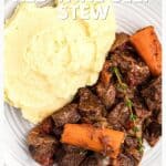 Plate of mashed potatoes and beef stew with carrots, garnished with herbs, on a white plate.