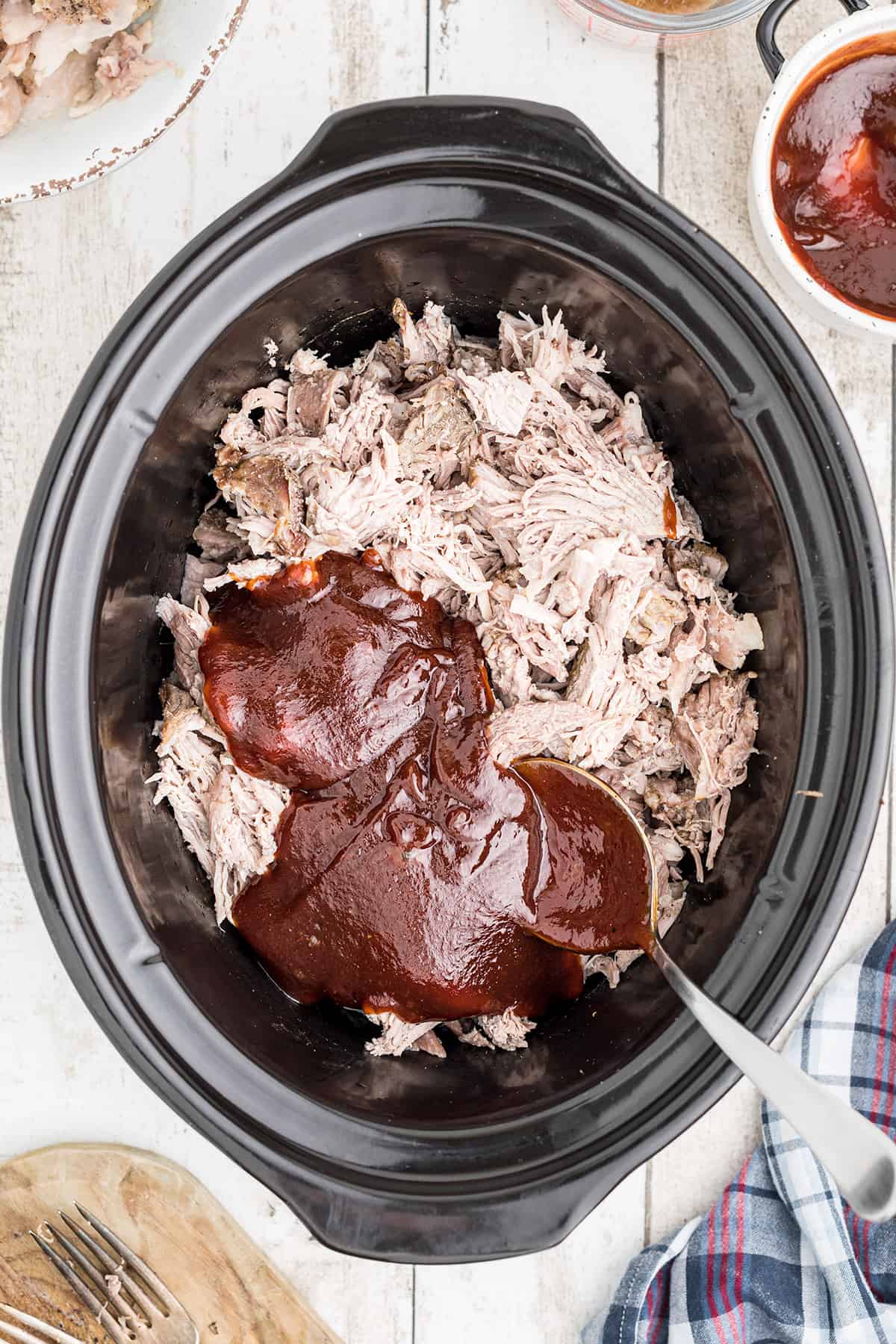 Barbecue sauce and cooking juices added to shredded pork in the slow cooker.