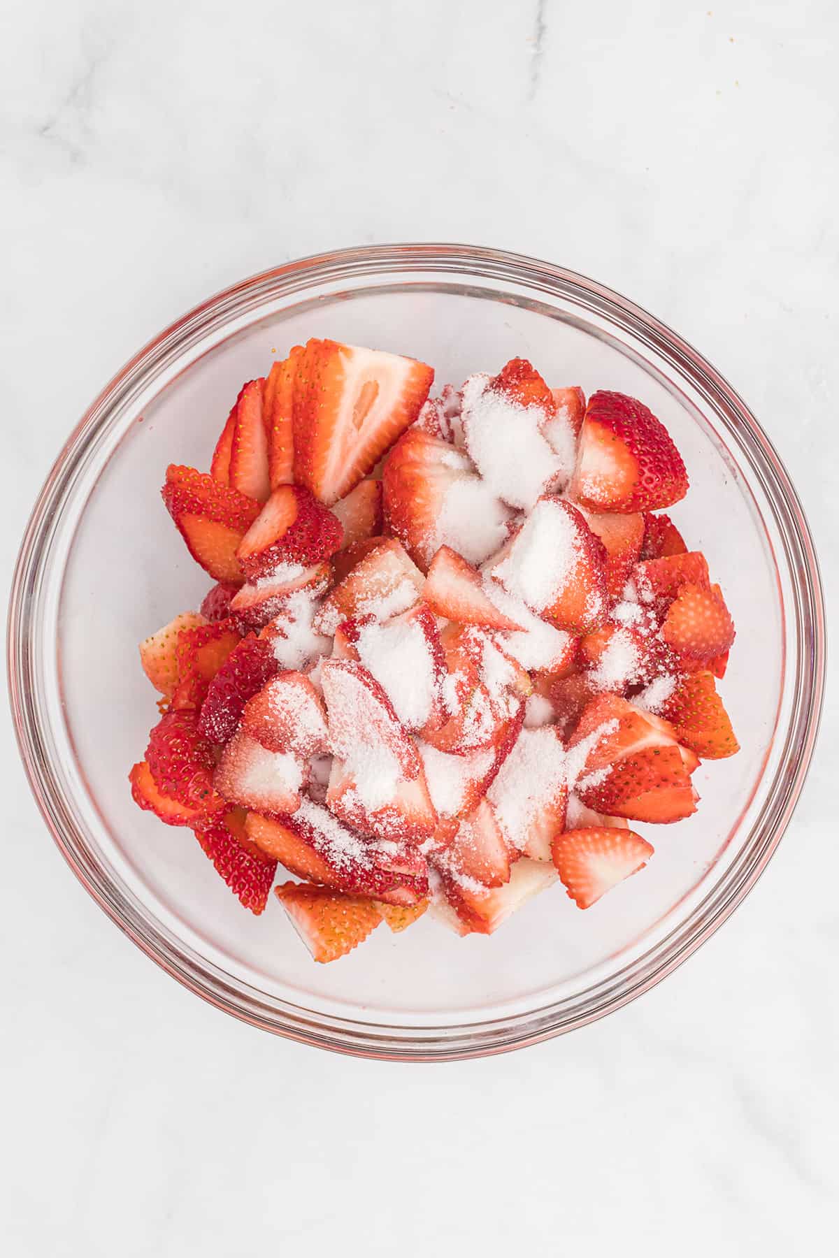 Strawberries with sugar sprinkled on top in a bowl.