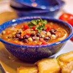 Black and white bean soup in a blue speckled bowl.