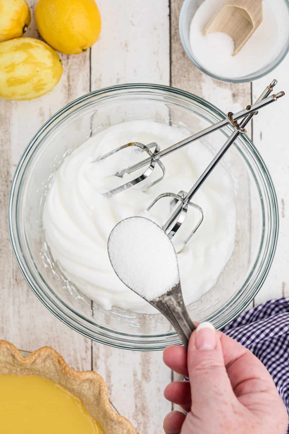 Adding sugar to the meringue.