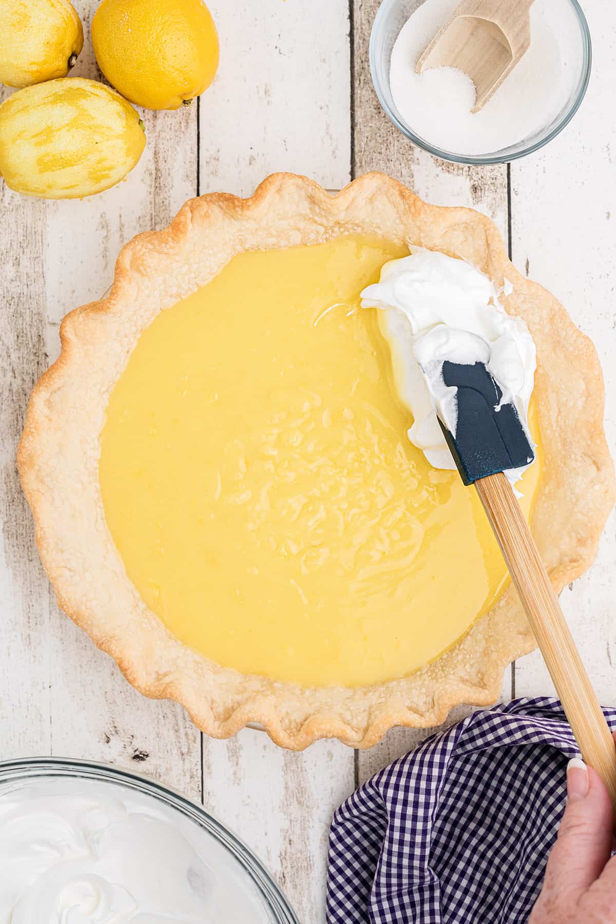 Spreading meringue on top of pie filling.