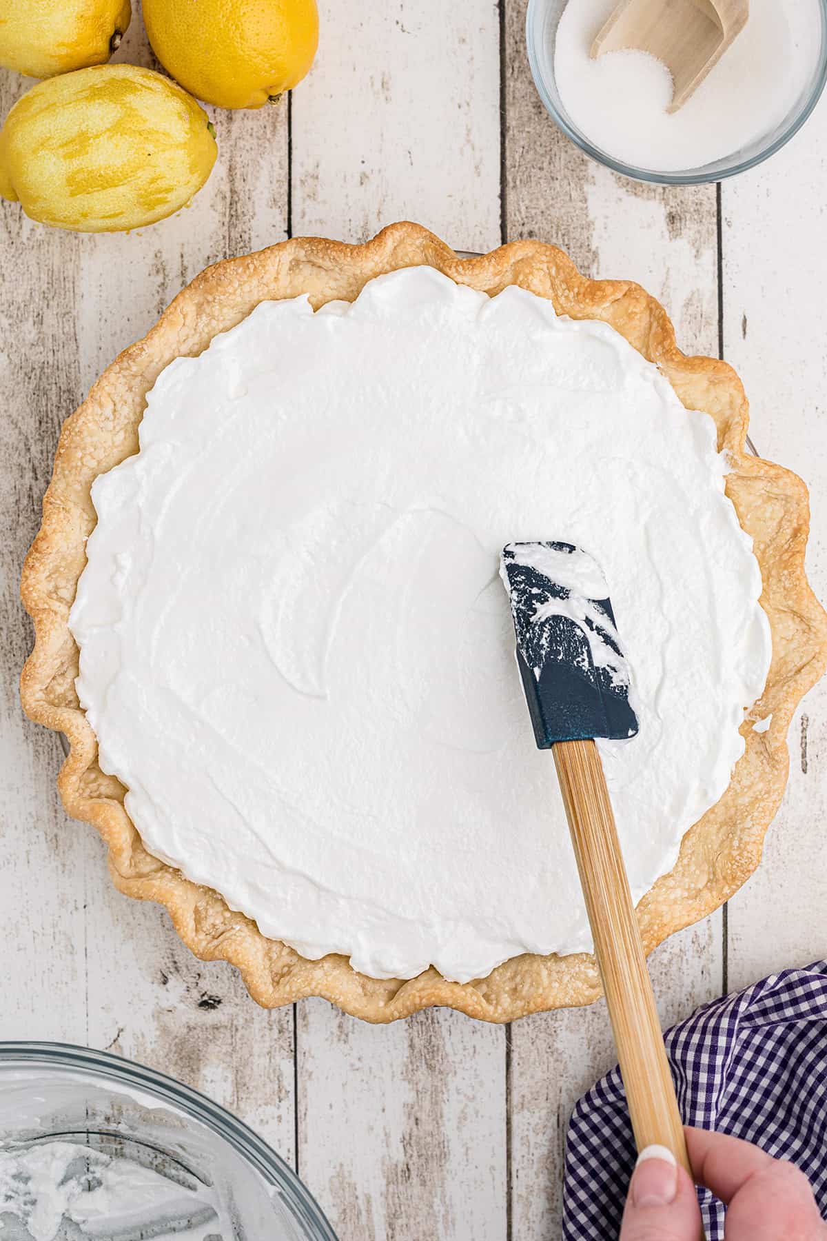 Spreading meringue on top of pie filling.