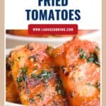 Slices of garlic fried tomatoes garnished with herbs, served on a white plate.