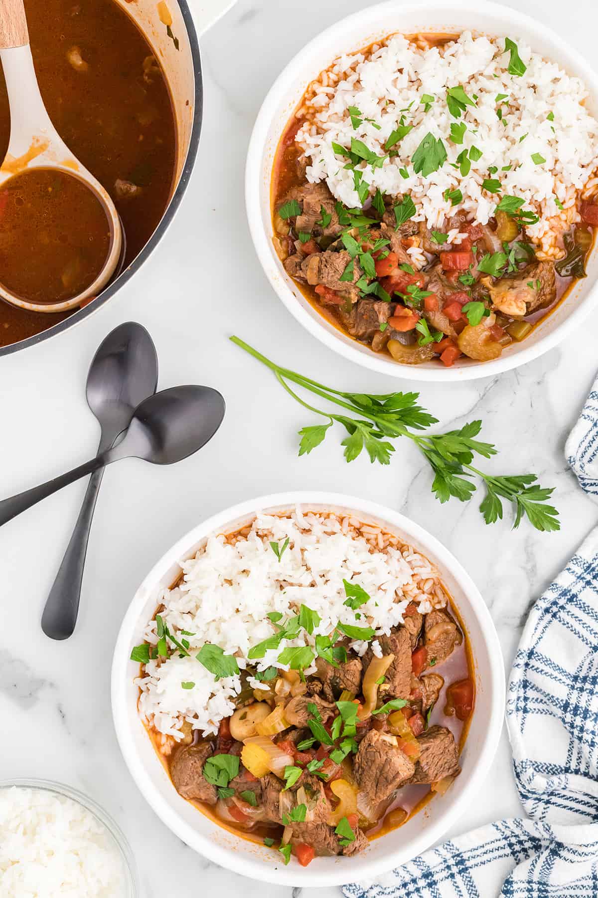 A serving of garlic lovers' beef stew over steamed rice in a white bowl.