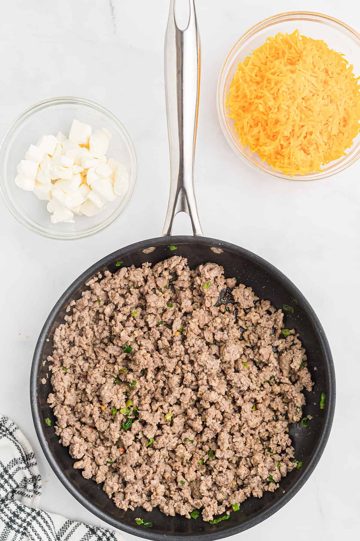 Sausage and cooked green onions in a skillet.