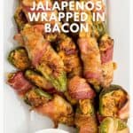 Bacon-wrapped jalapeños stuffed with sausage and cheese, served on a white platter with dipping sauce.