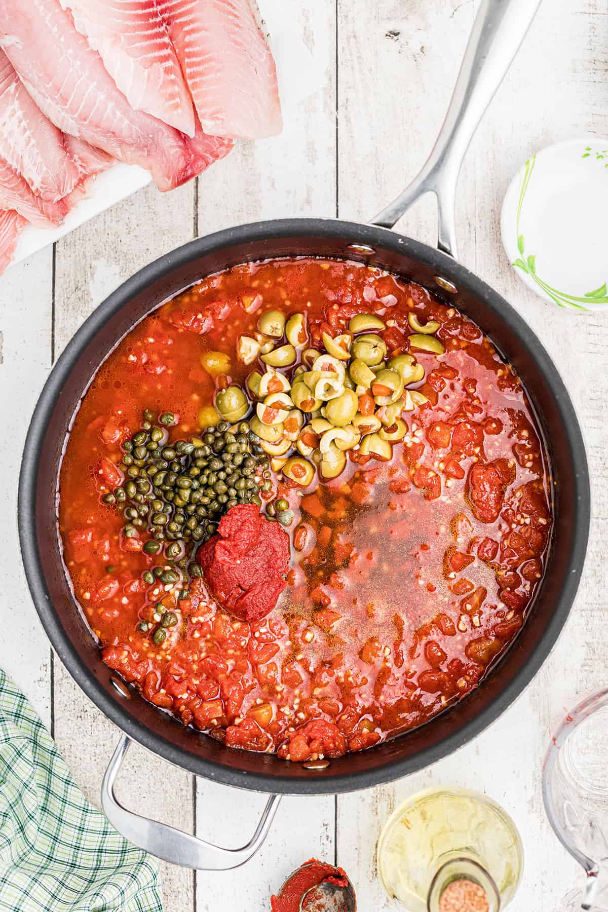 Tomatoes with olives and capers added to skillet.