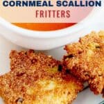 Two crispy cornmeal scallion fritters on a plate with a bowl of tomato soup, garnished with basil.