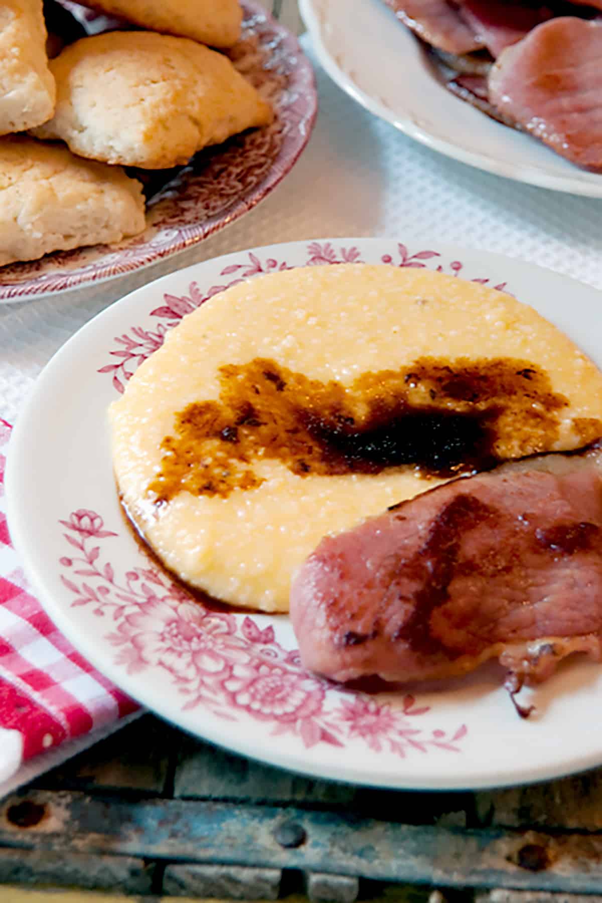 Ham and red eye gravy with cheese grits on a serving plate.