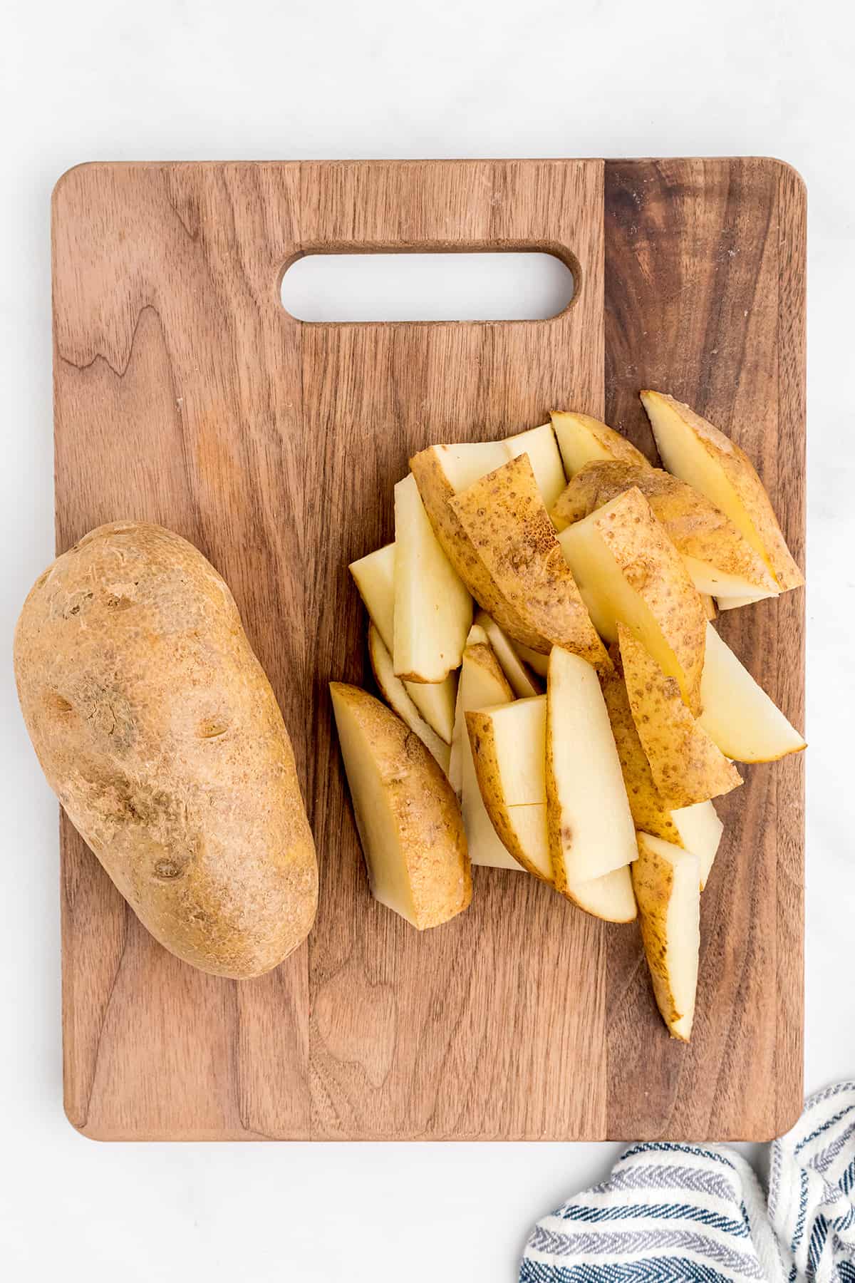 Clean potatoes cut into wedges on a board.