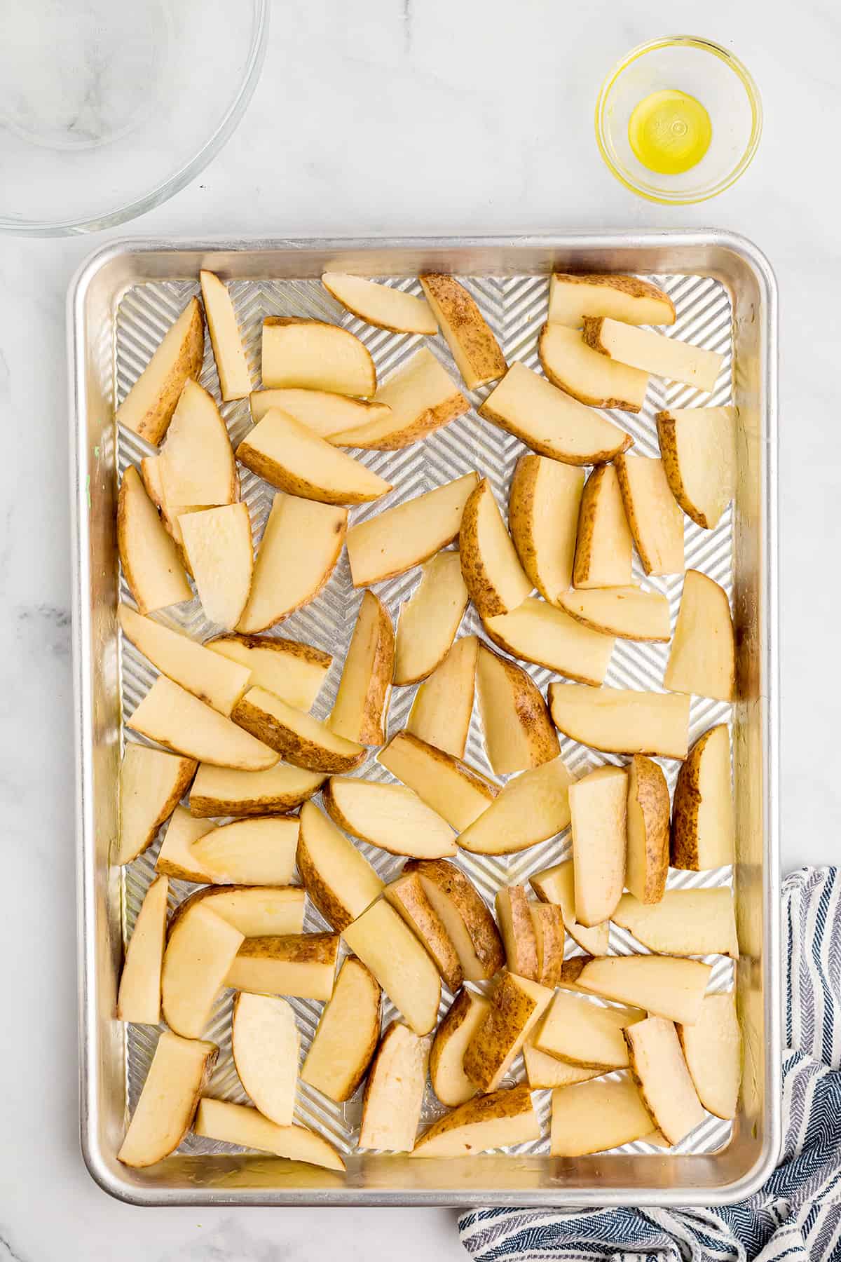 Potato wedges on the prepared baking pan.