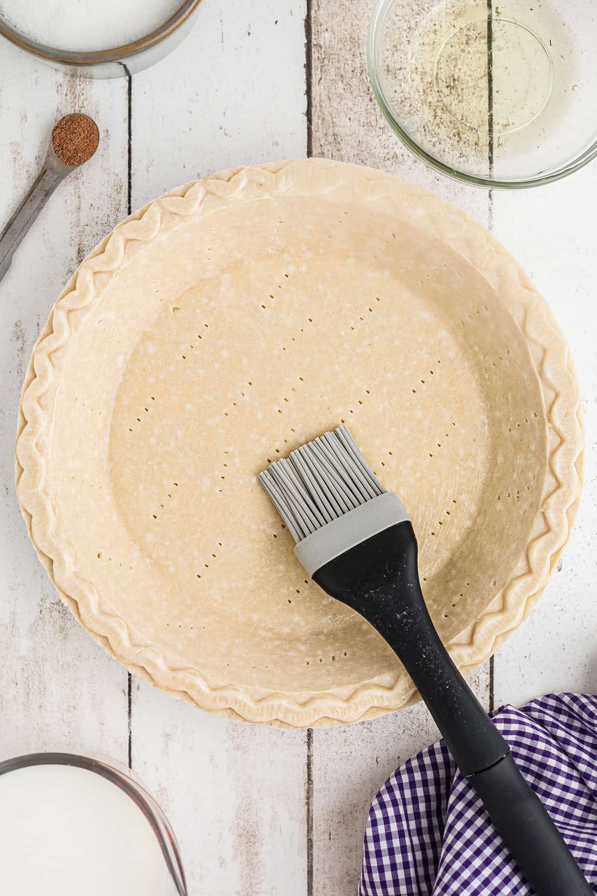 Pie crust being brushed with egg white.