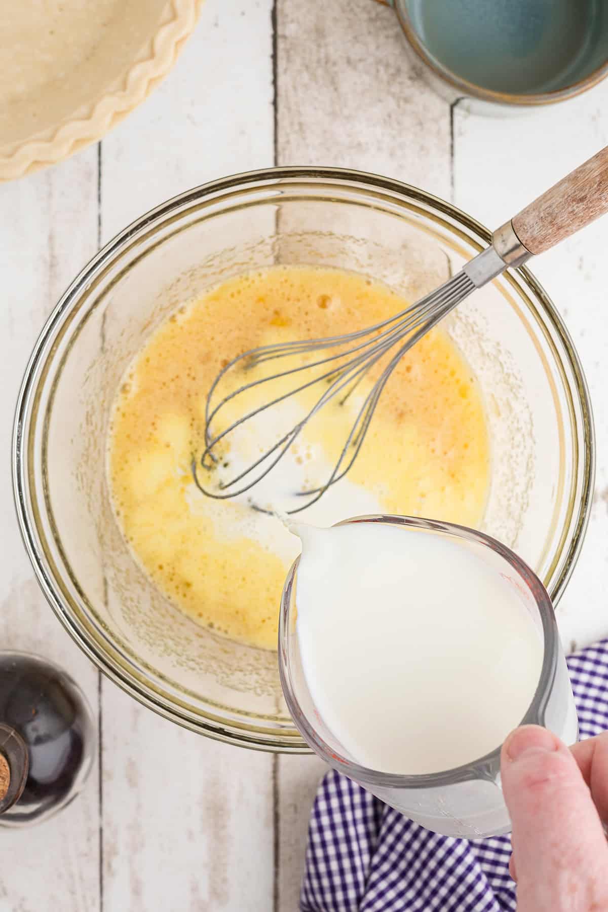 Whisking milk into the egg mixture.